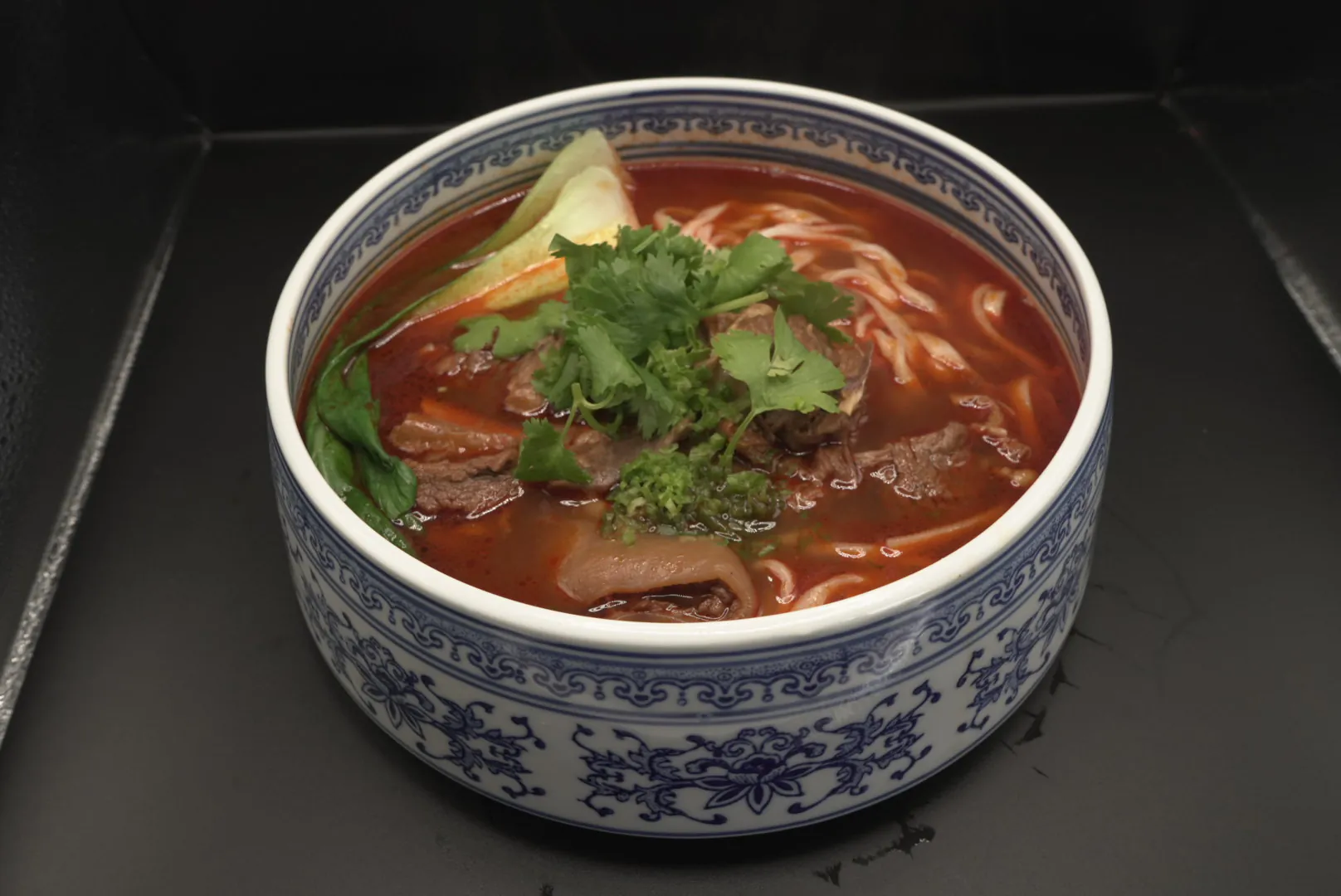 Spicy beef noodle soup with cilantro and vegetables at Lao Hu Tong, a Asian Restaurant in Schaumburg